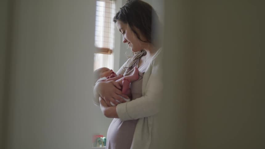 Pregnant woman holding a baby in a room near a window