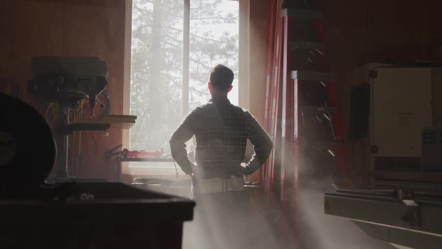 A man stands and looks out the window