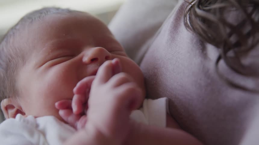 A woman holds a newborn baby in her arms