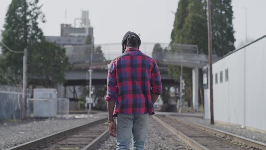 Man walks through town between railroad tracks