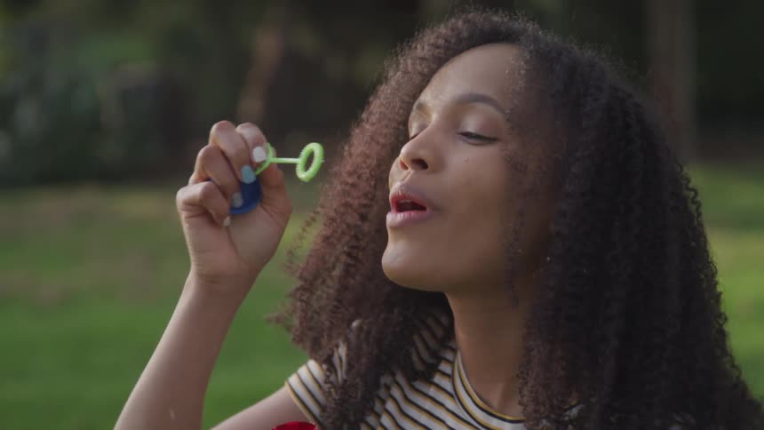 Teenage girl blowing soap bubbles