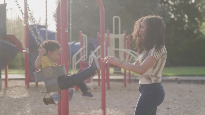 Mother pushing a boy child onswing