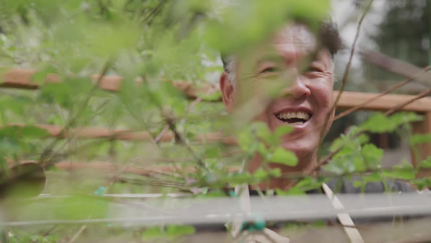 An asian man sits on a bench laughing and talking with a woman