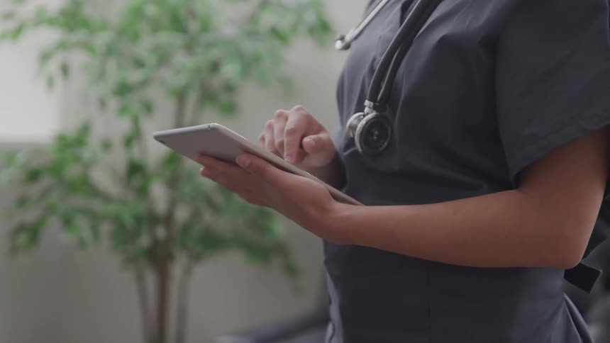 A female nurse scrolls through at tablet