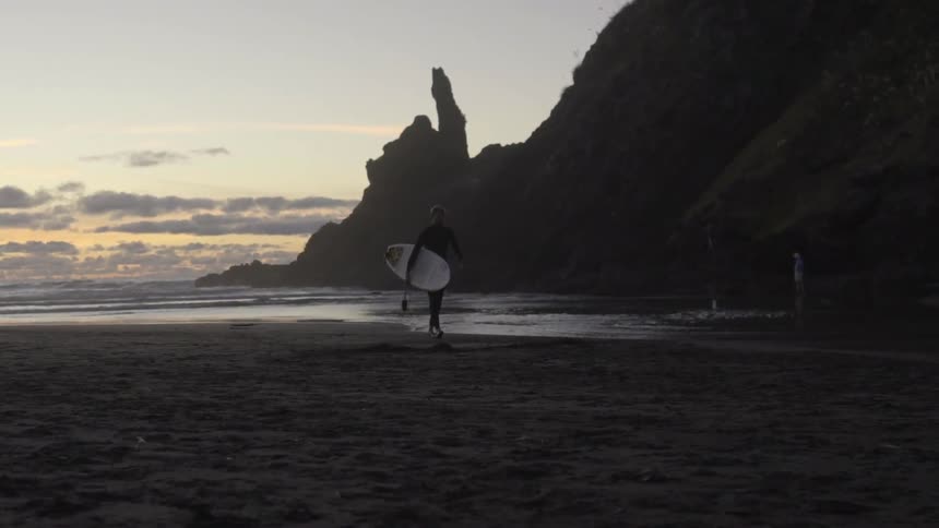 A person Walking along the shoreline of a beach, with gentle waves and a relaxed atmosphere.