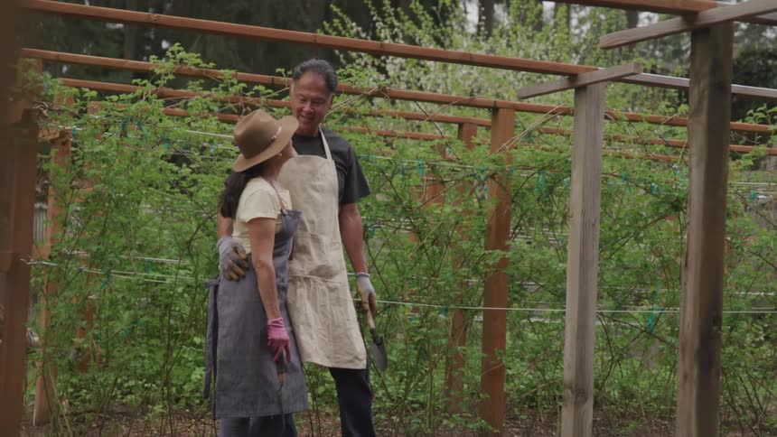 A man and woman stand in a vineyard talking