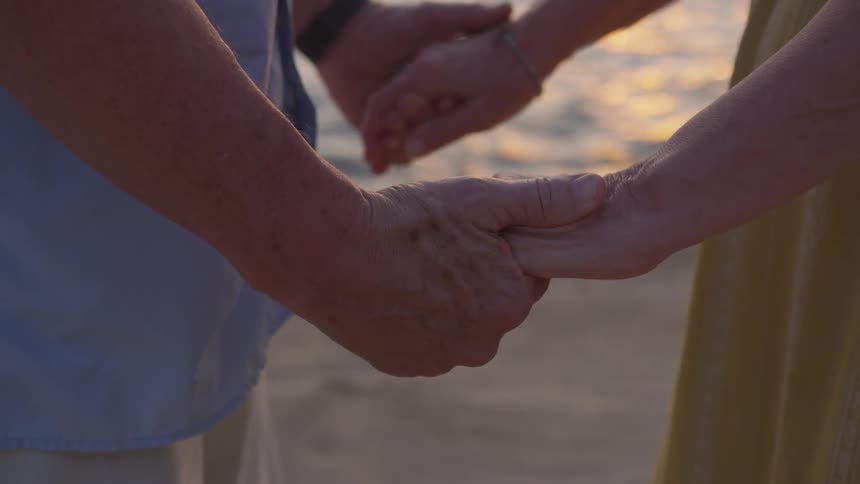 A couple holds hands standing by the ocean coast line
