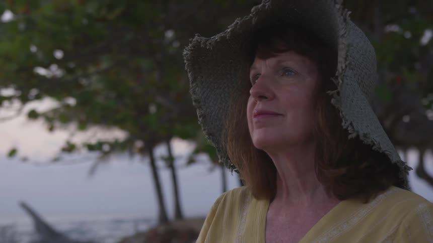 An old woman with a hat blankly stare at the sky