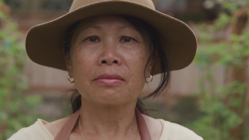 Asian woman wearing a hat in her garden