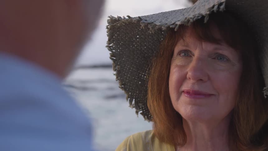 A woman smiles staring at a man by the shore