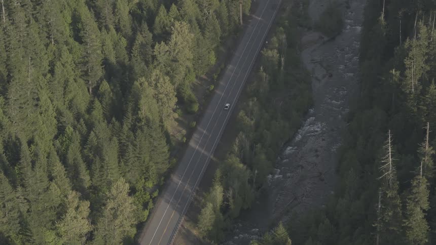 An aerial view of a car traveling on a road in a forested area