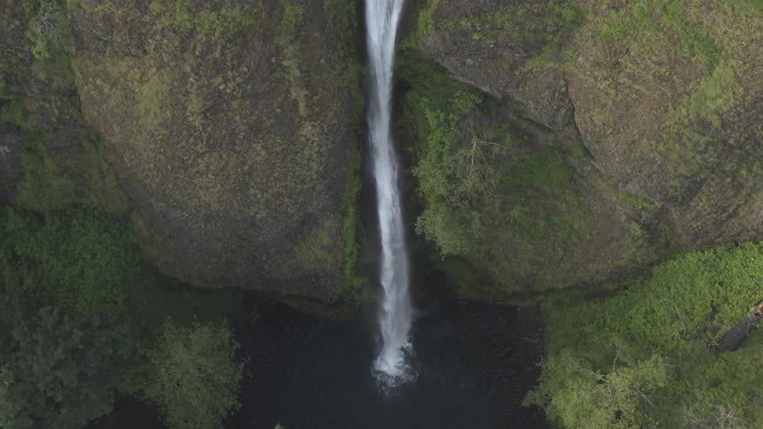Narrow waterfall plunges down sheer cliff to pool