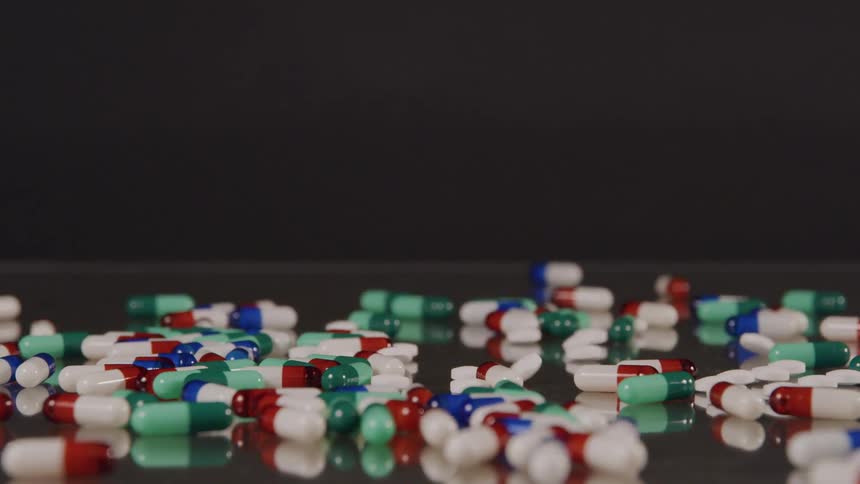 Pills falling on a mirrored surface