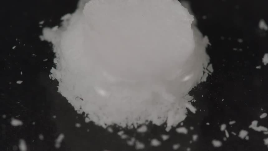 A round white pill begins to dissolve in liquid and bits float away