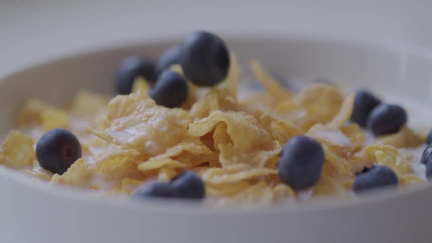 Blue berries dropping into cereal