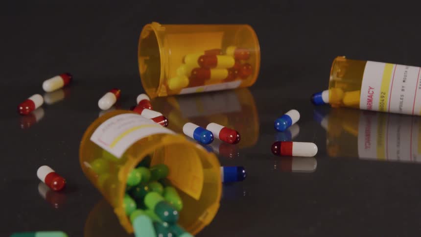 Medication bottles fall to a table and the pills spill out