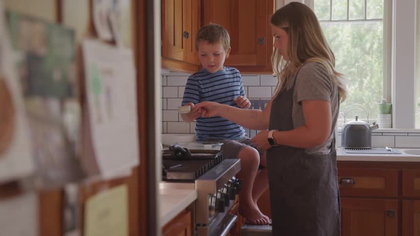 A child helps his mother cook in a kitchen