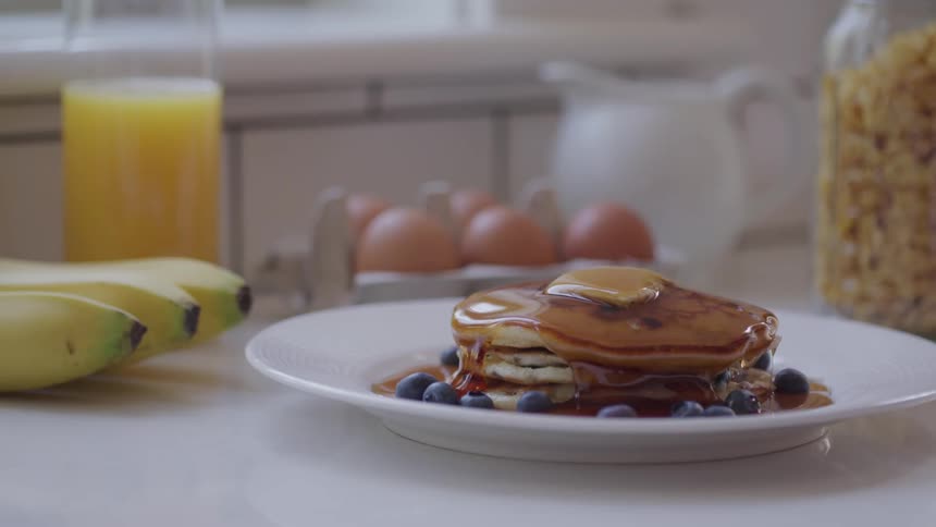 Syrup being poured on pancakes