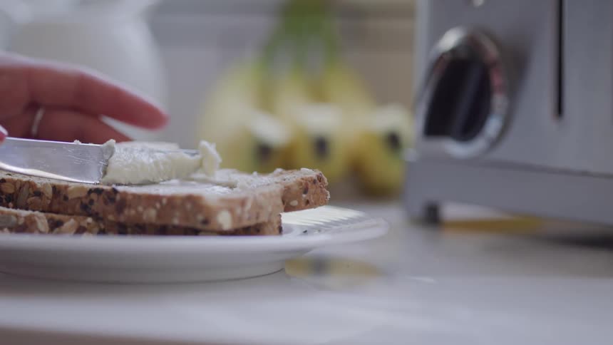 A person spreads butter on bread