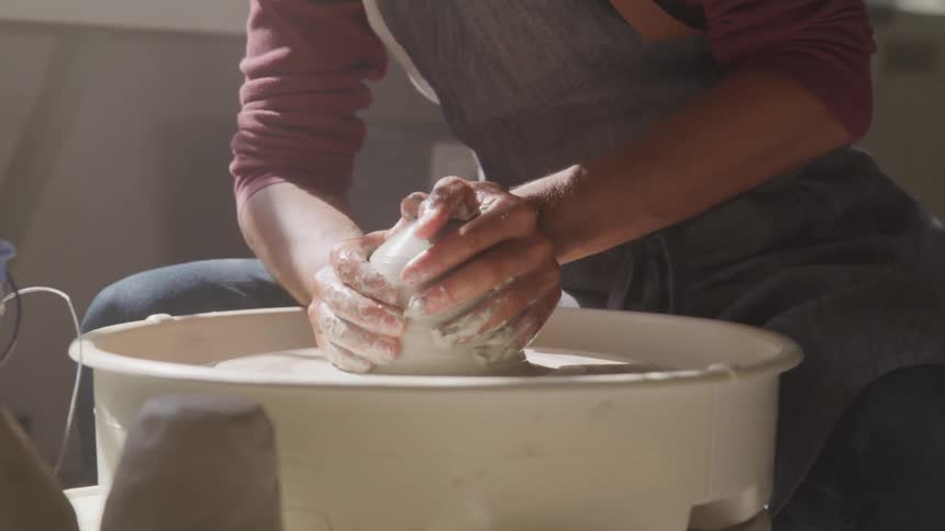 A man shapes clay on a spinning pottery wheel
