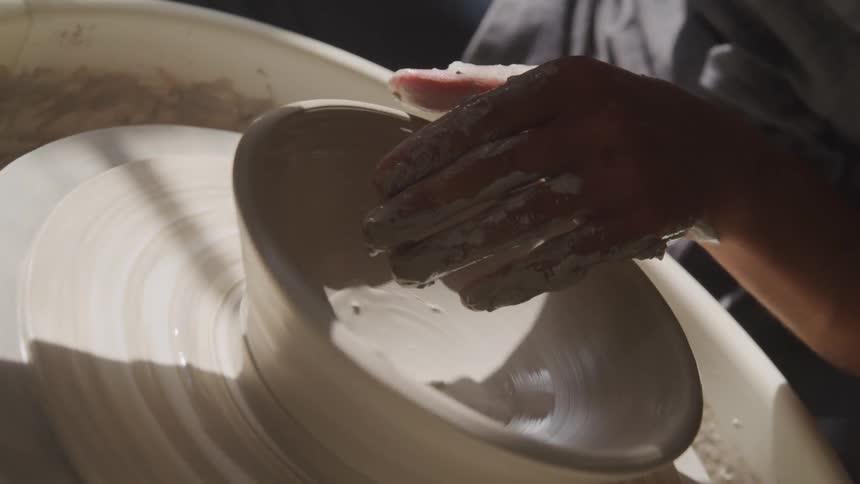 A person turning clay on a pottery wheel