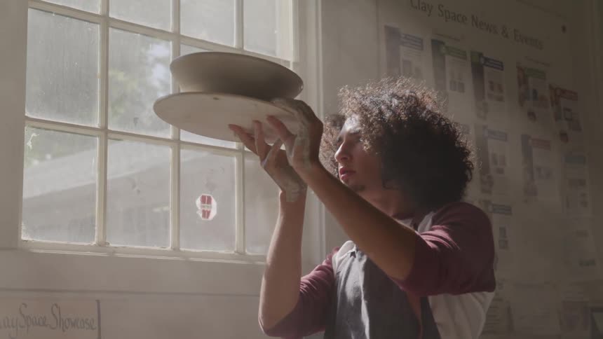 A man holds a piece of pottery up to inspect it closely