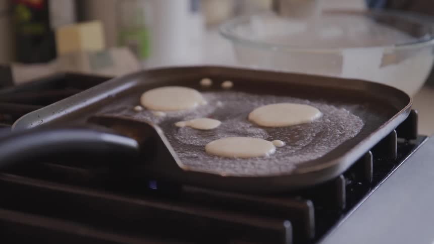 A person pours pancake batter on to a griddle