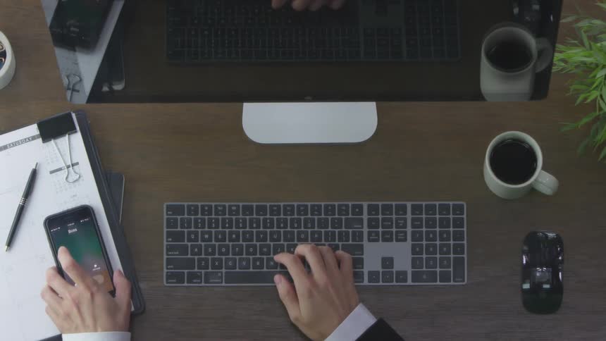 A person works at a desk then answers a cell phone
