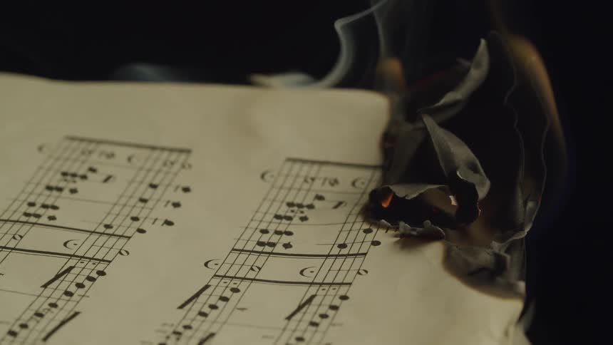 Sheets of music burning and being extinguished with water