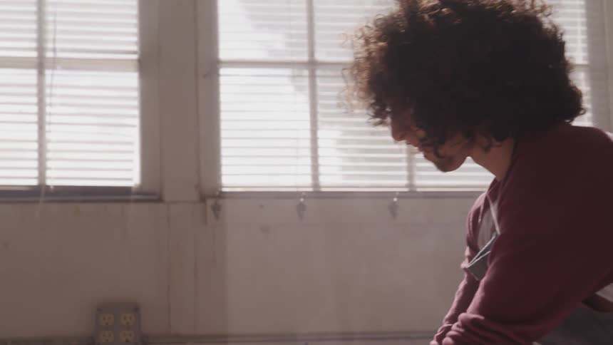 A curly haired man working on something
