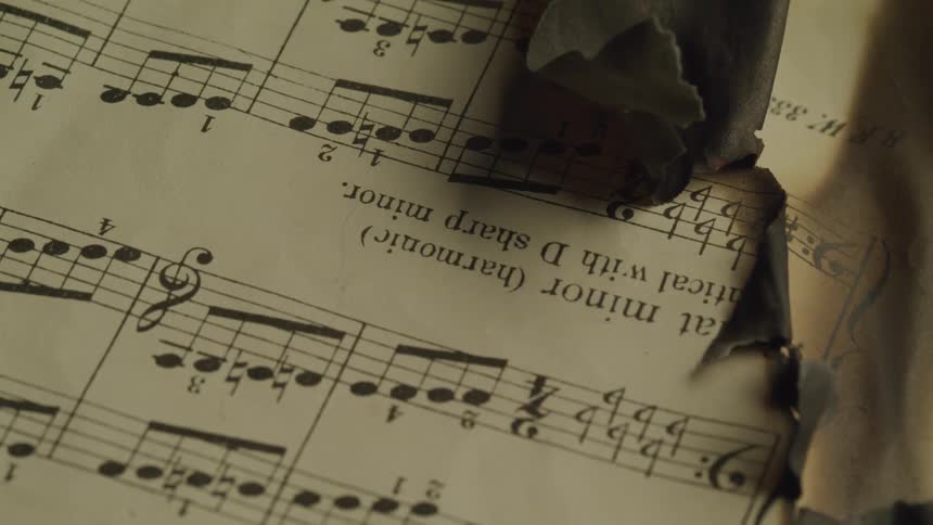 A sheet of music slowly being engulfed by flame