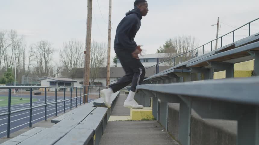Black man runs up the steps between the bleachers