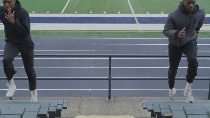 Two men run up bleachers