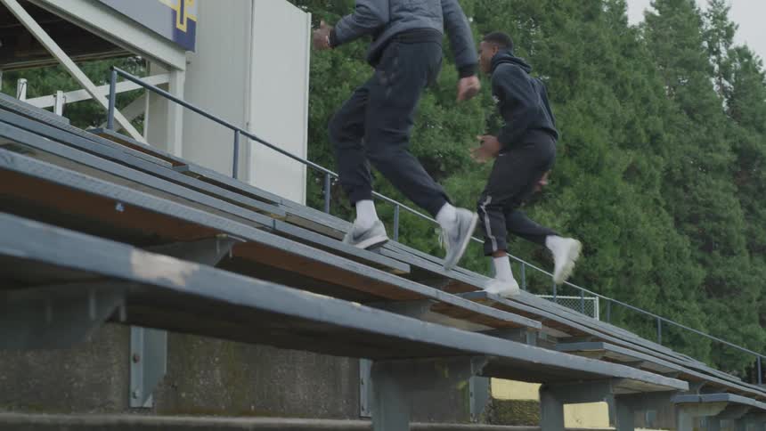 Two young men running up bleachers for exercise