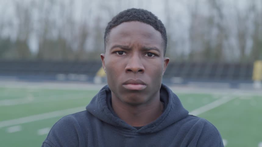 A man is standing outdoors in a sports field