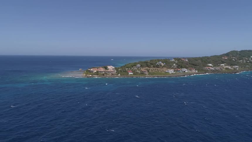 The ocean with a peninsula with buildings and trees in the background