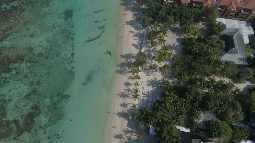 Beach houses with swimming pools and condos beside a waterway and white beach