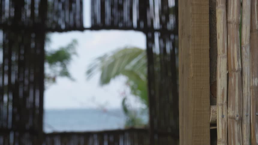 A window in a wooden hut faces the ocean