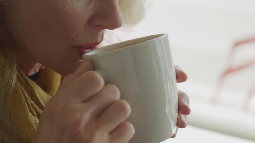 Blonde woman drinks coffee in a cafe during daylight