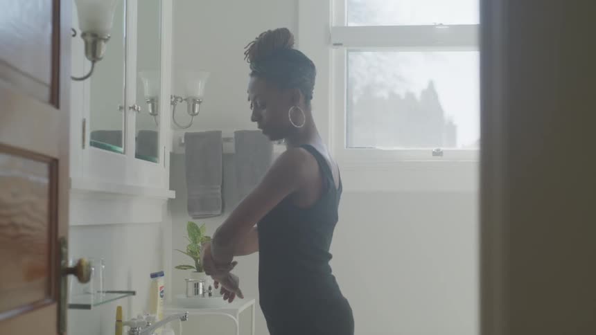 A young black woman gets washed at a sink