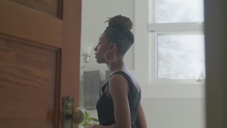 Black woman looks in the mirror indoors during daylight