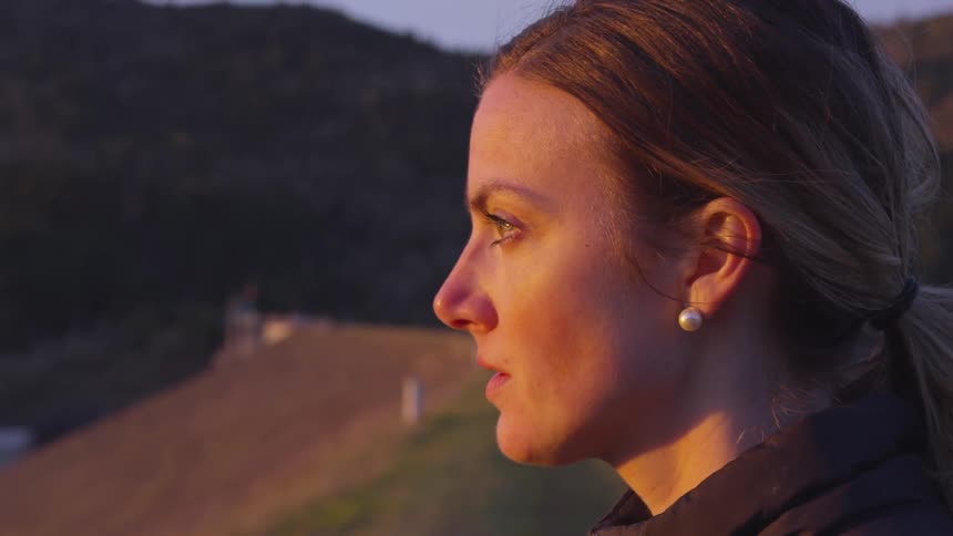 A woman lifts her head and looks off in to the distance