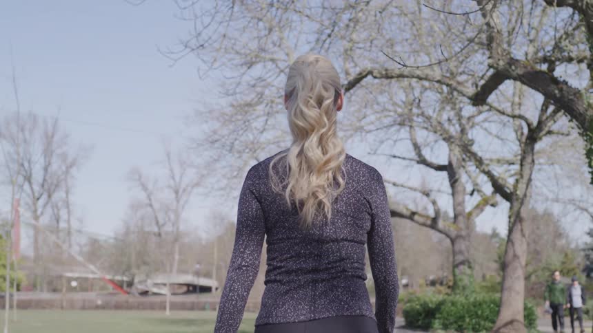 A woman walking through a park on a sunny day