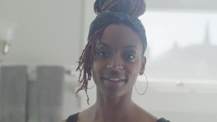 A black woman with dreadlocks smiles