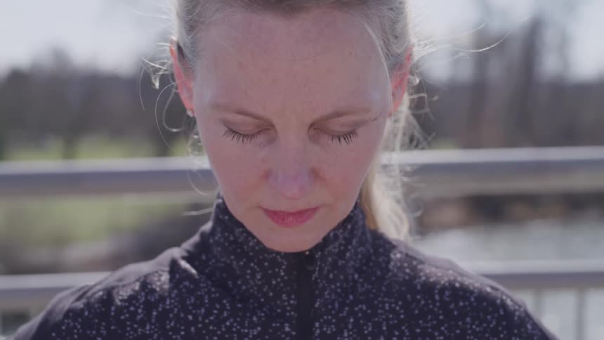 A woman stands with her eyes closed