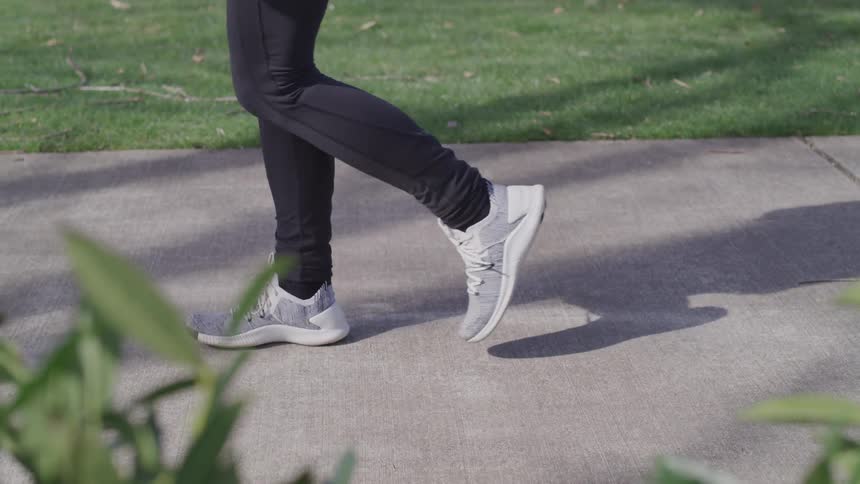 Walking down the sidewalk in black pants and gray sneakers