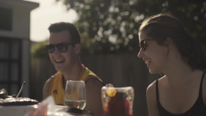 Man and woman wearing sunglasses laughing at a picnic table