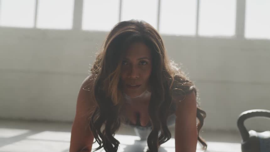 Brunette woman does planks while the sun streams through the window