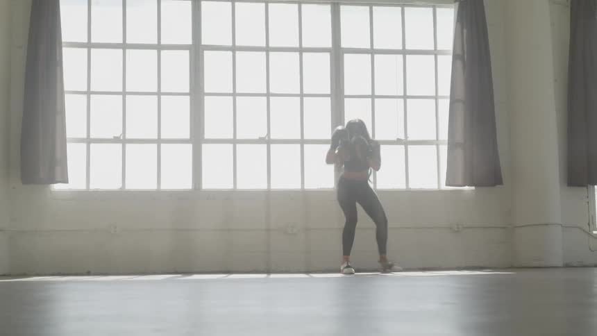 A woman boxes alone in a gym