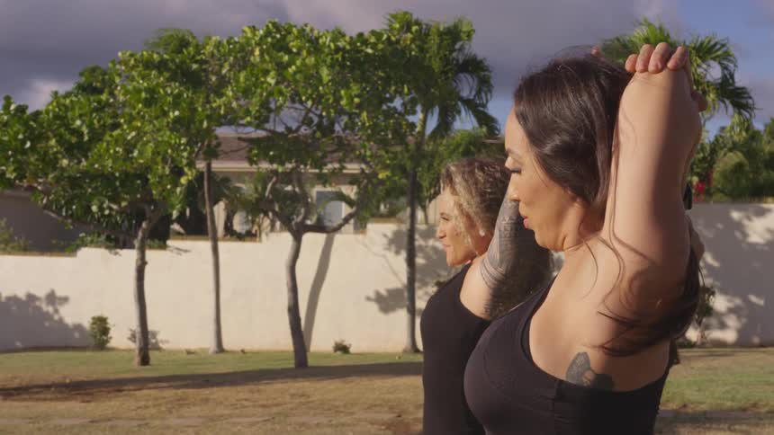 Two women standing on the grass stretching